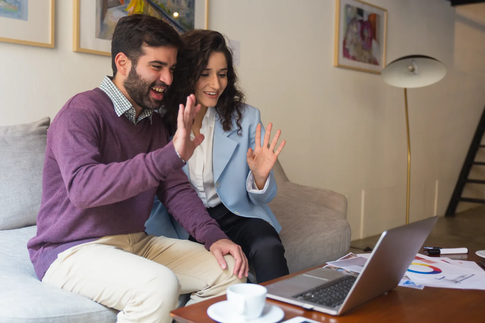 Pareja saludando a su asesora en una videollamada desde casa